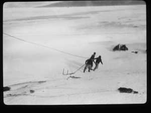 Image: Three men hauling large hook across snow